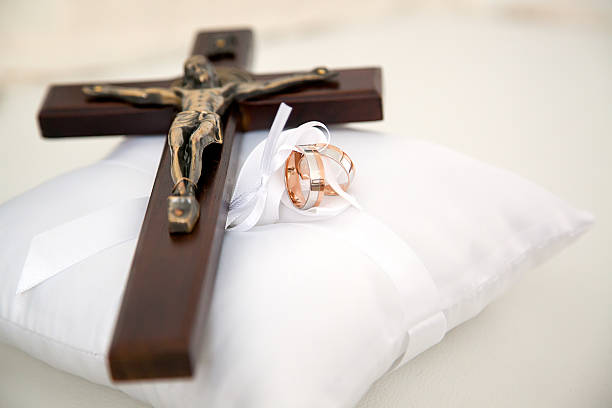 istock Christian cross and wedding rings on white cushion 626303376