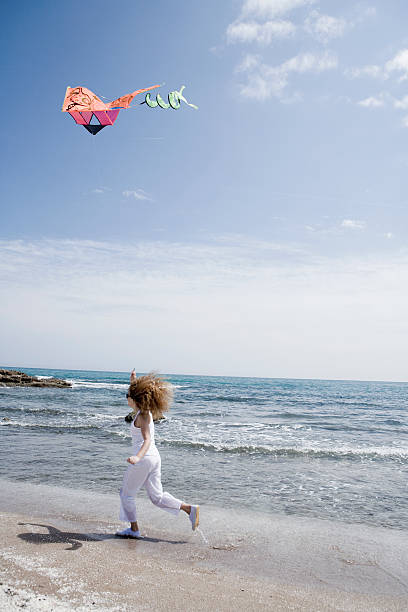 istock Young woman flying kite at the beach 626310442
