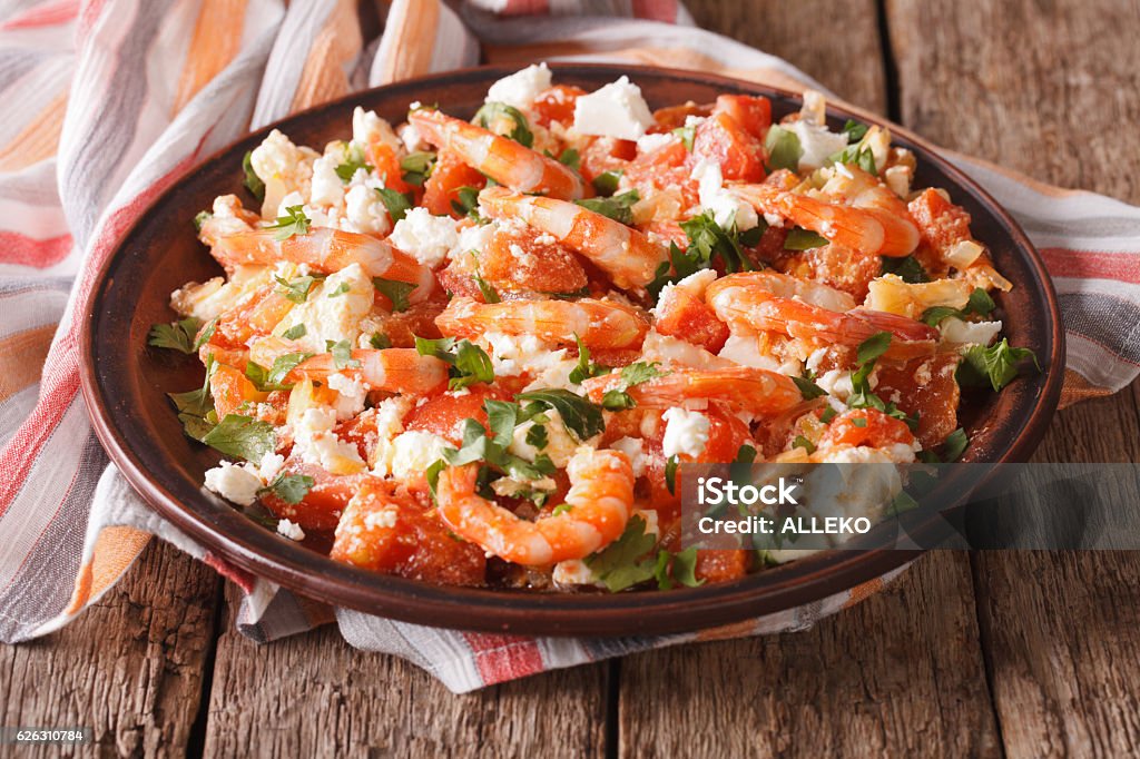 Shrimp with tomatoes and feta cheese on a plate close-up Shrimp with tomatoes and feta cheese on a plate on a table close-up. horizontal Baked Stock Photo