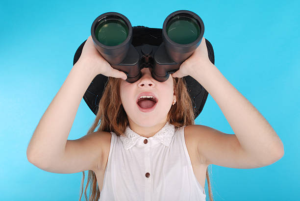 istock Beautiful young girl  looking through binoculars with surprised expression 626321156