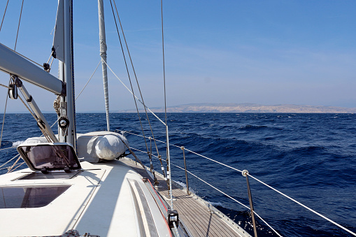 A detail of a sailboat sailing in the Adriatic sea past the rocky island