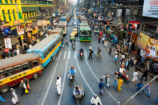 Calcutta, India - January 20, 2013: Pedestrians cross the road in front of motorcycles, cars and buses at the crossroads on January 20, 2013 in India. Kolkata has a density of 814.80 vehicles per km road length