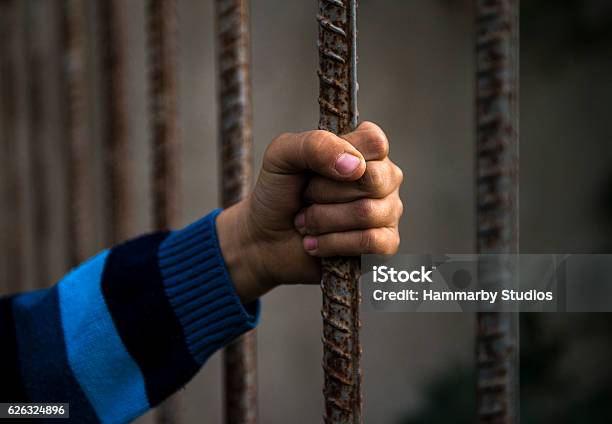 Side View Of A Child Gripping Grate Stock Photo - Download Image Now - Refugee, Child, Slavery