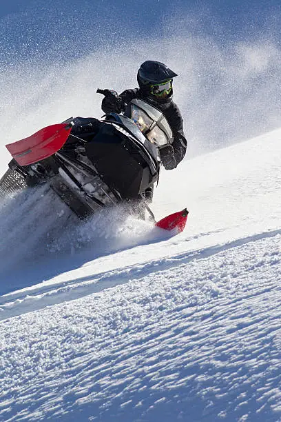 A man rides his snowmobile up a steep hill in Canada.