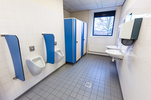 Toilet room for men with urinals sinks and towel dispenser on high school. I took this photo in the netherlands on high school where I work. I waited for a day that there were no people because the students were on holidays. This is the toilet room for men and boys.