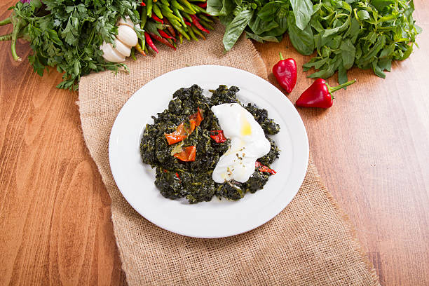 Boiled spinach on white dish with yogurt and wood decor, top view