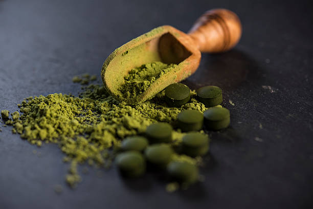 Organic Spirulina Powder and Tablets Organic spirulina powder and tablets shot on a slate chlorella stock pictures, royalty-free photos & images