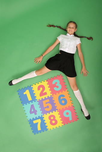 School girl is lies in front of a rug with numbers on green