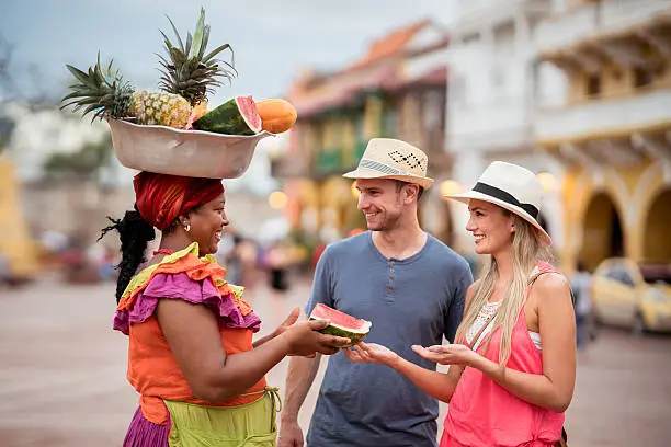 Couple of tourist buying fruits in the street and talking to a palenquera un Cartagena - travel like a local