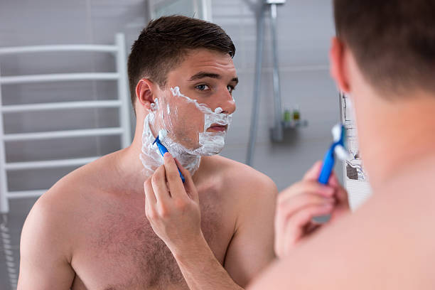 istock Male shaving his face and looking at the mirror 626351872