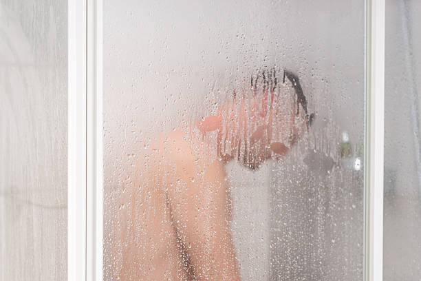 istock Male taking a shower standing behind transparent misted glass 626351940