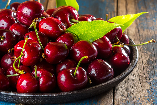 Fresh cherry on black plate on wooden background. Close up
