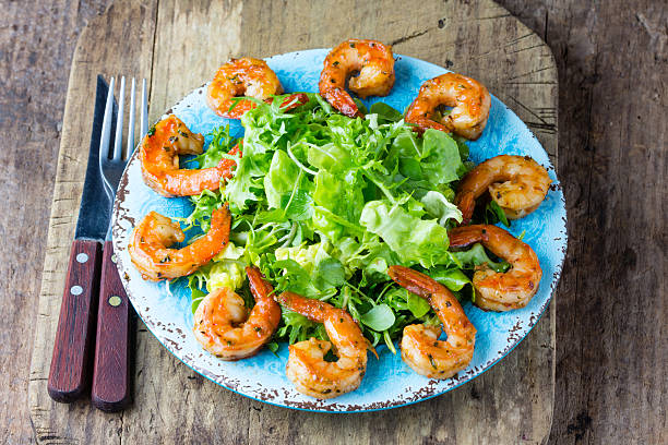 istock Srimp lettuce salad on blue plate, wooden rustic background 626362080