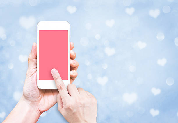 istock Hand holding mobile phone with finger touch on pink screen 626367340