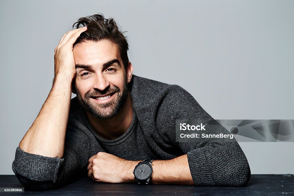 Smiling guy in grey Smiling guy in grey sweater, portrait Hand In Hair Stock Photo