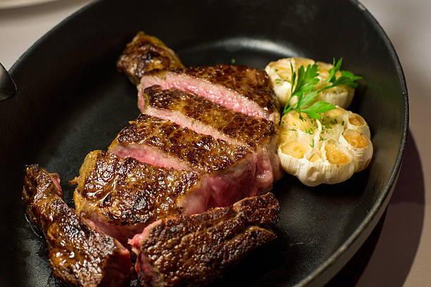 istock Sliced steak with roasted garlic on black plate 626394886