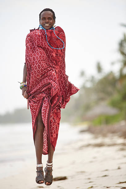 eleganter maasai-mann springt am strand von sansibar. - masai africa dancing african culture stock-fotos und bilder