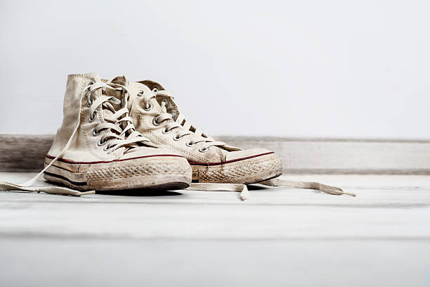 istock Old white sneakers on wooden background 626400470