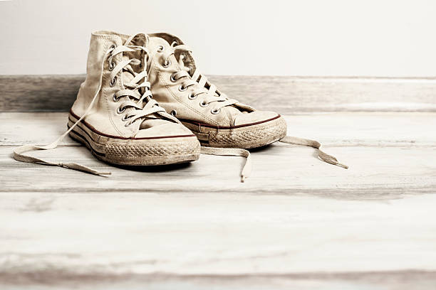istock Old white sneakers on wooden background 626400620