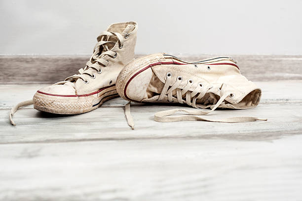istock Old white sneakers on wooden background 626400778