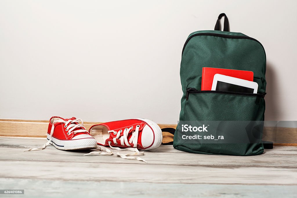 Red sneakers with school bag on wooden background Backpack Stock Photo