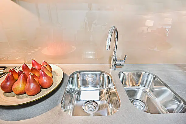 Photo of Fruits and sink with designs on kitchen table.