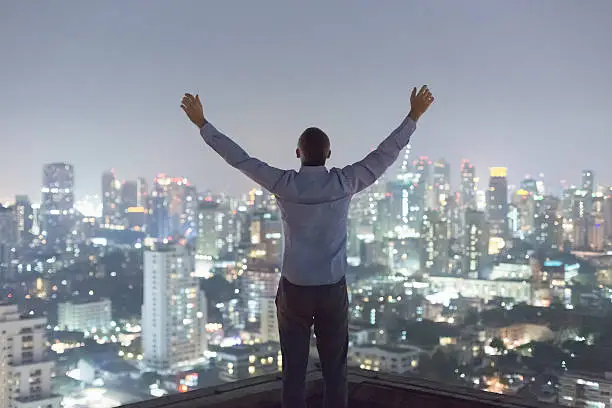 Photo of Man over top skyscraper, arms raised