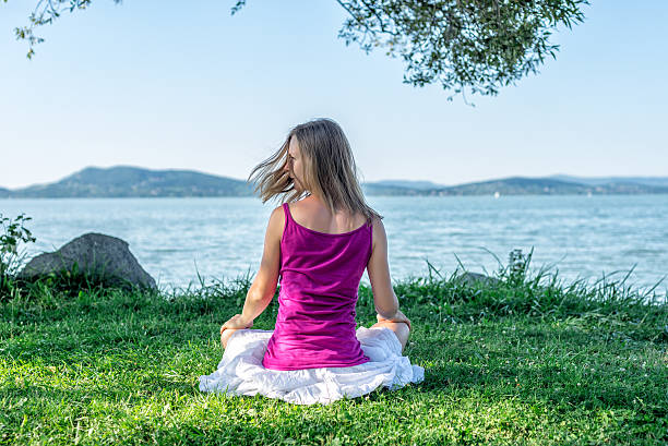 donna meditare sul lago - equanimity foto e immagini stock