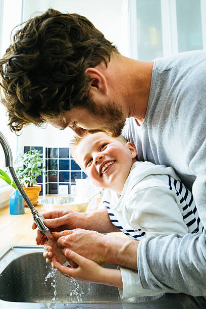 istock Father Washing Sons Hands In Kitchen Sink After Cooking Together 626416282