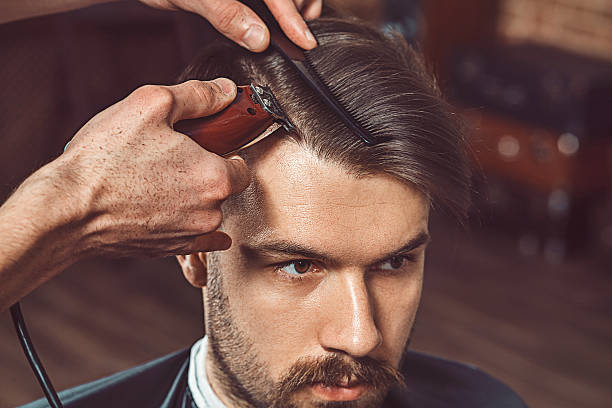 Hipster client visiting barber shop Hipster client visiting barber shop. The hands of young barber making the cut of beard men hair cut stock pictures, royalty-free photos & images