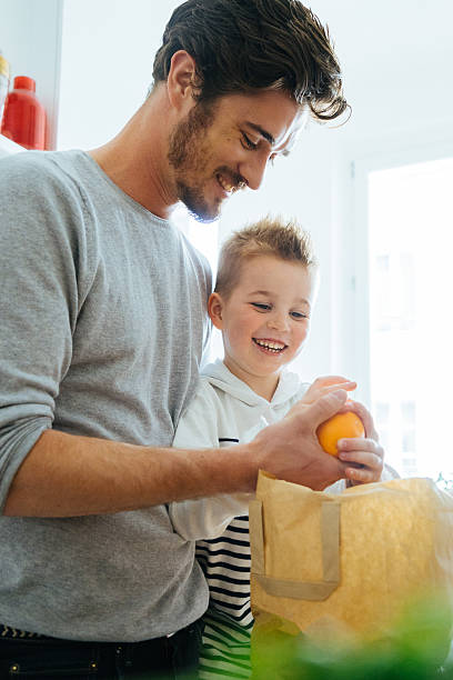 istock Father And Son Organizing Groceries In The Kitchen 626421478