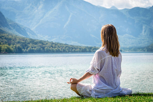 istock Woman meditating at the lake 626421666