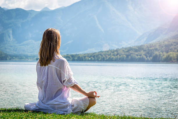 istock Woman meditating at the lake 626423106
