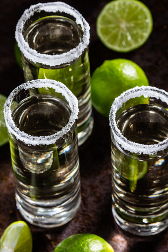 Tequila shots with lime and sea salt on rustic background, selective focus