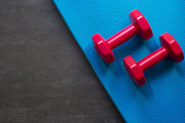 istock red dumbbell and blue yoga mat on black background 626425228