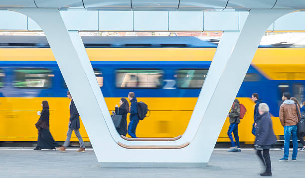 Train passing passengers on the platform at the station stock photo