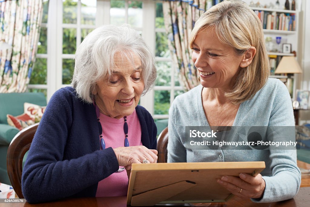 Senior Woman Looks At Photo In Frame With Mature Senior Woman Looks At Photo In Frame With Mature Female Neighbor Picture Frame Stock Photo