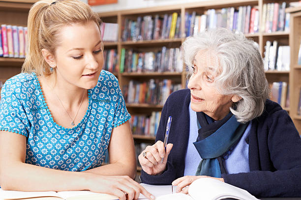 istock Senior Woman Working With Teacher In Library 626440200