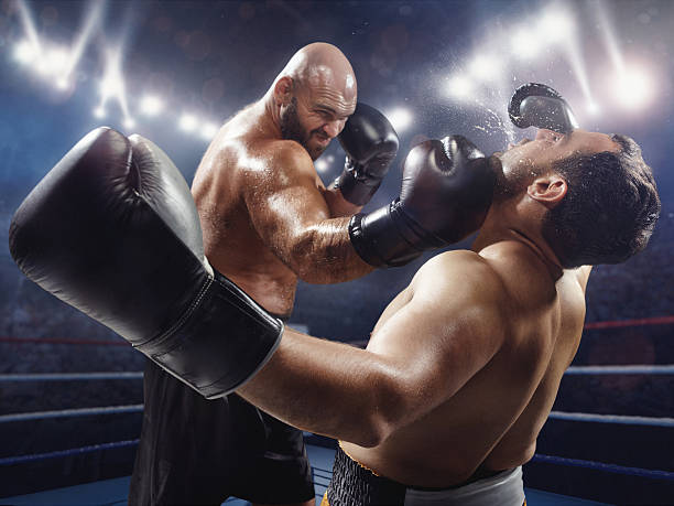 Boxing: Extremely powerful punch The action takes place on a professional ring with high weight sportsmen.  A sportsman in yellow shorts kicks off the soul of the opponent. All wear unbranded cloth and sport equipment boxing referee stock pictures, royalty-free photos & images