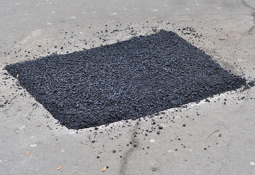 Close up on asphalt  road repair. Repair pavement and laying new asphalt patching method outdoors.