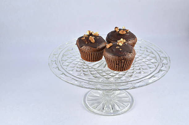 istock three chocolate brown muffins with nuts on glass plate 626444550