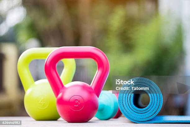 Kettlebell Dumbbell And Yoga Mat On Wood Table Stock Photo - Download Image Now - Outdoors, Exercising, Health Club