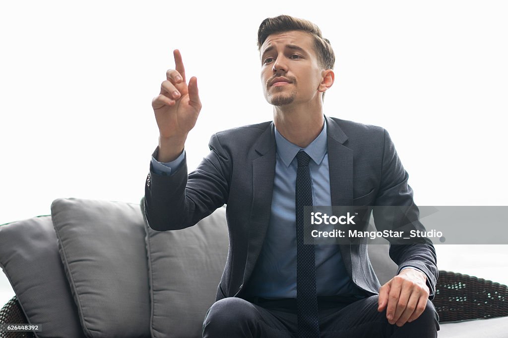 Successful Man Trying to Get Waiters Attention Portrait of successful young man wearing suit, sitting in cafe, trying to get waiterÃ¢ÂÂs attention with raising hand gesture Men Stock Photo