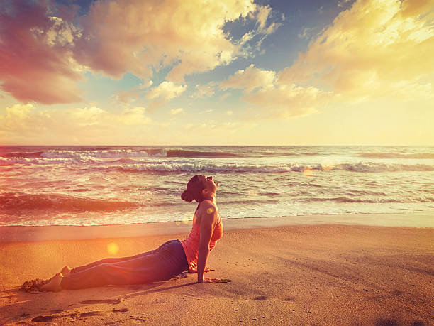 femme pratiques yoga asana urdhva mukha svanasana à la plage - salutation au soleil photos et images de collection