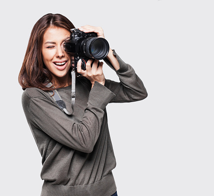 Young woman photographer looking at camera, isolated on gray background