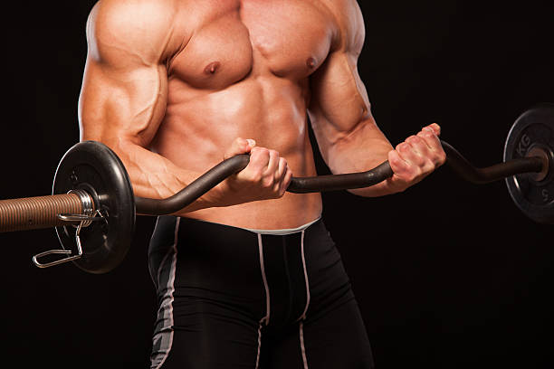 istock Muscular male athlete is training by lifting the barbell 626462824