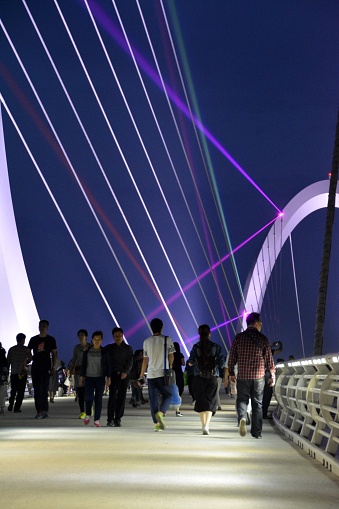 Nanjing, China - June 5, 2016: People sightseeing the Postmodern Nanjing Eye pedestrian bridge, lighten at night, which connects the Cultural and Sports Park of YOG in Hexi New Town of Nanjing and Jiangxinzhou Youth Forest Park.  