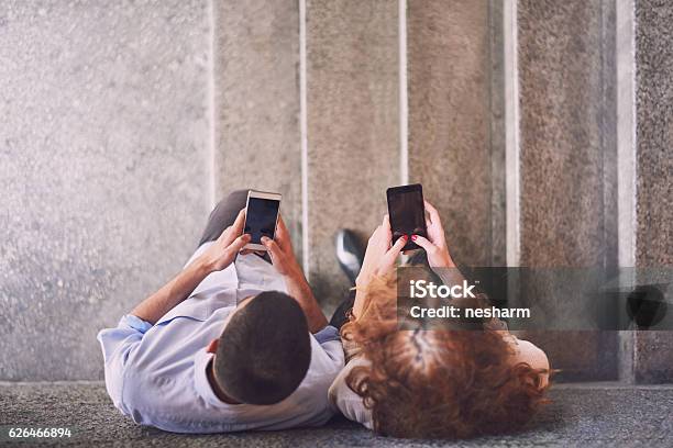 Young Couple Texting Messages Over Smart Phones Stock Photo - Download Image Now - Two People, Aerial View, Smart Phone