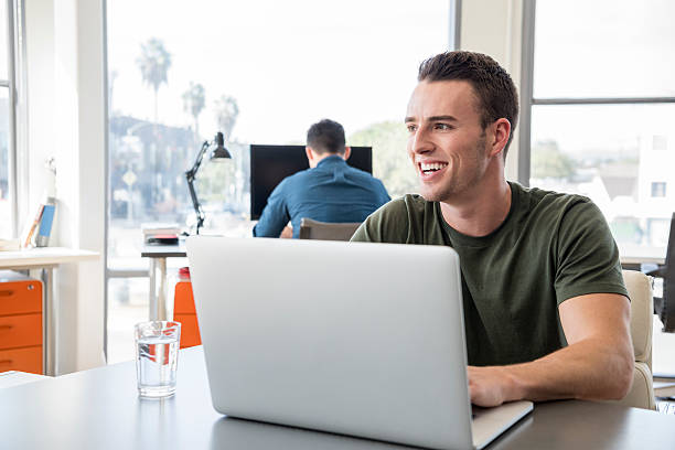 istock Young businessman using laptop and looking away laughing 626468776