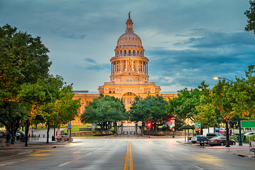 Photo of the facade of the Texas State Capitol building in downtown Austin, Texas, USA, illuminated at twilight.